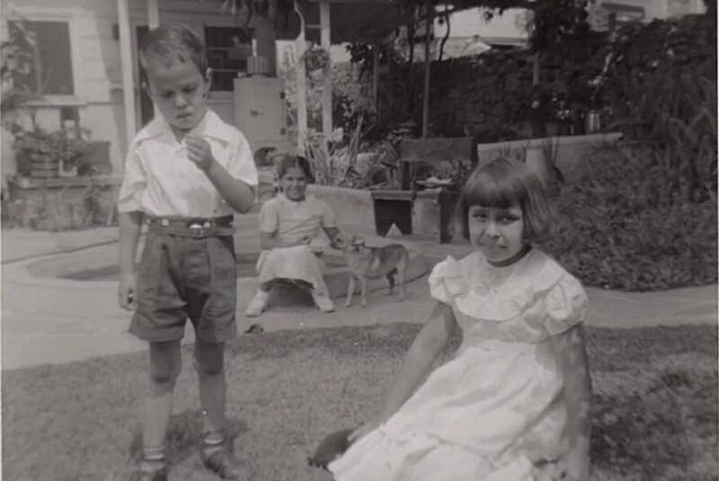 Siblings Lawrence “Buddy” (left) and Carol (right) are in the foreground, while their neighbor Lolita (middle) sits with the family dog, Blondie, on a raised cement flower planter in their lawn under an avocado tree. Courtesy Carol Jacques, Chavez Ravine: An Unfinished Story archival collection
