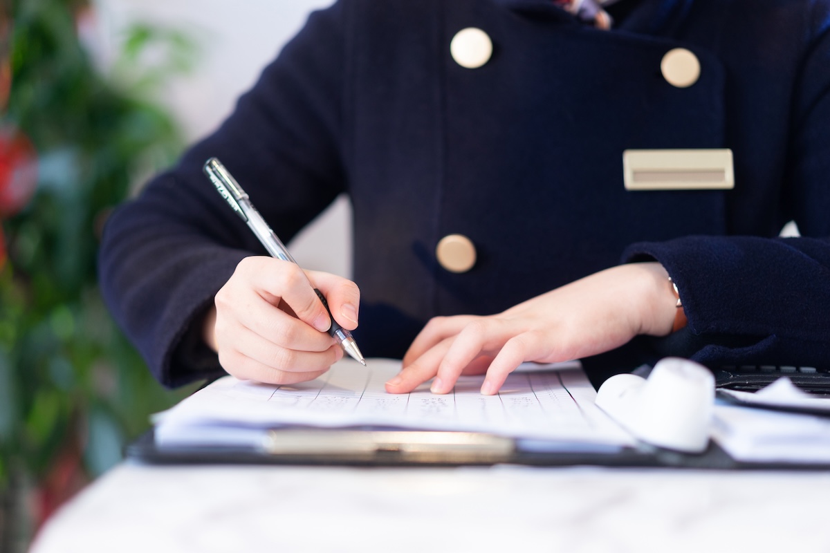 Hotel worker writing in notebook at counter