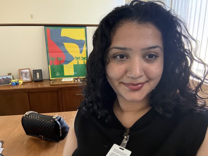 Rikisha Chahal smiling at desk in internship office