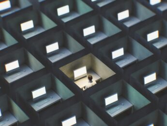 Surreal image of office cubicles with man working late. 3D generated image.