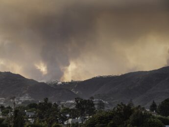 View from Santa Monica of wild fire in Pacific Palisades, a suburb of Los Angeles, in the Santa Monica mountains. The fire is burning in mountainous terrain densely covered by chaparral brush, and is close to many homes