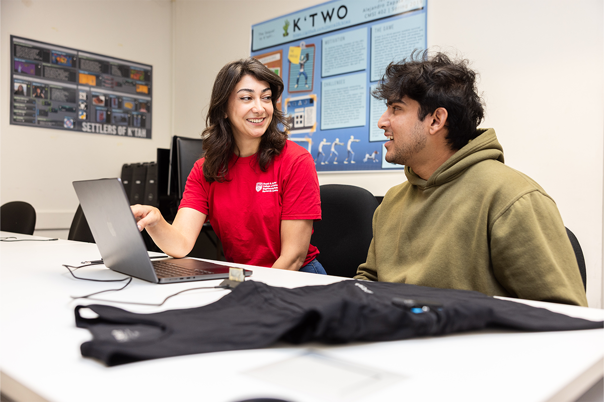 Delaram Yazdansepas, assistant professor of computer science, sitting next to computer science student Dayyan Chaudhri in the lab looking at a laptop