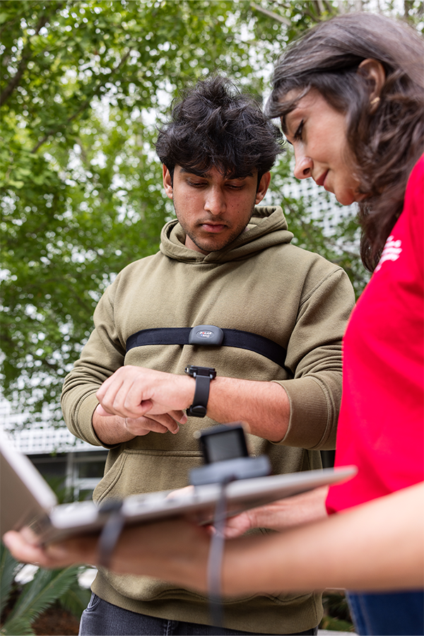 LMU student wearing a chest strap sensor and watch sensor standing next to professor holding laptop