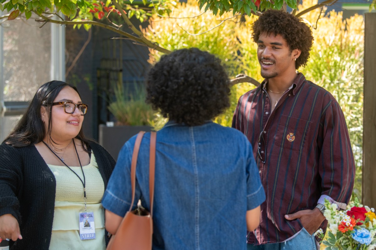 Miles Gibson outside talking to two women