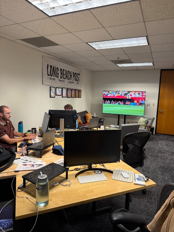 tables, desk, TV, and a couple of reporters in Newsroom