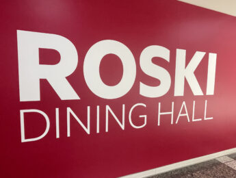Close-up of a bright red wall featuring large white lettering that reads ROSKI DINING HALL
