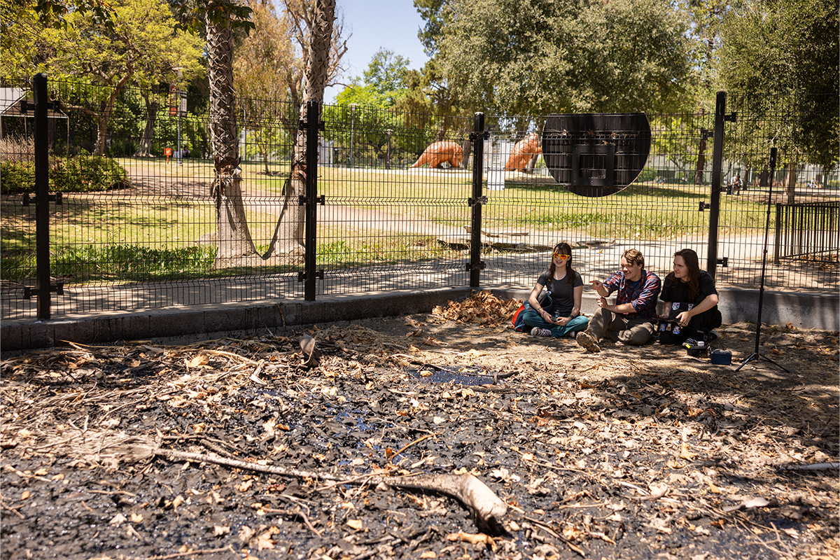 Two LMU environmental science students sitting with professor near tar pit in LA's La Brea Tar Pits