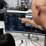 over the shoulder image of a professor and student looking at a monitor of code