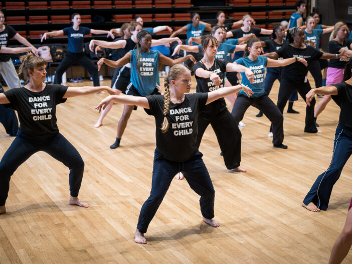 Group of women in T-shirts that say "Dance For Every Child" dancing in a studio