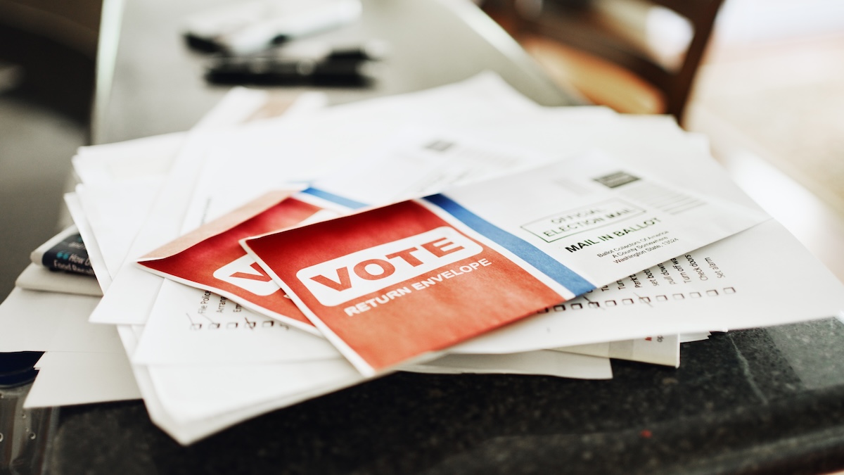 Voting ballot and other mail sitting on a stack on a kitchen counter of a home
