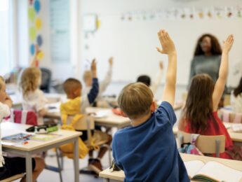Students raising hands in classroom