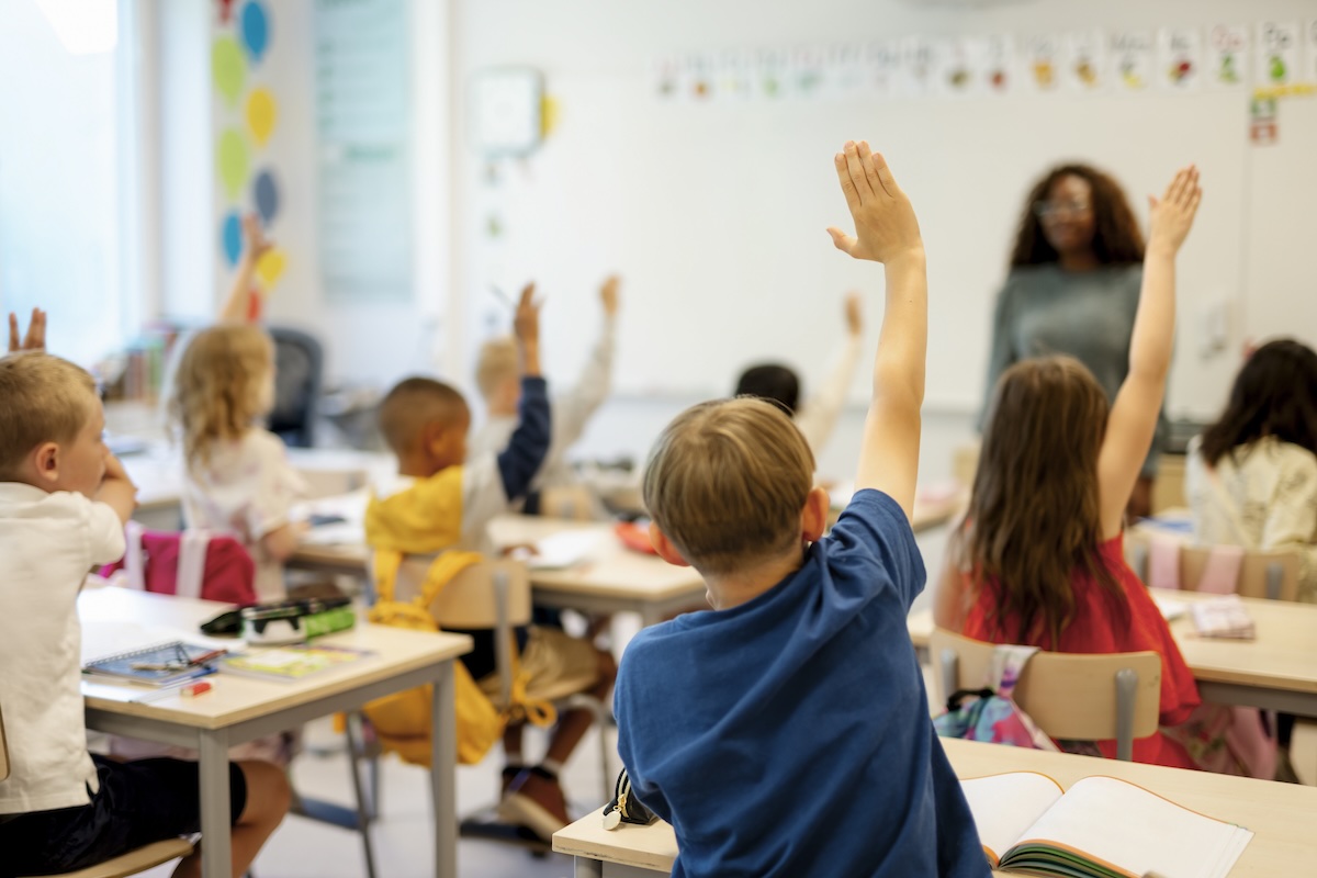 Students raising hands in classroom