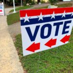 Red, white and blue sign with an arrow indicating where to go to vote.