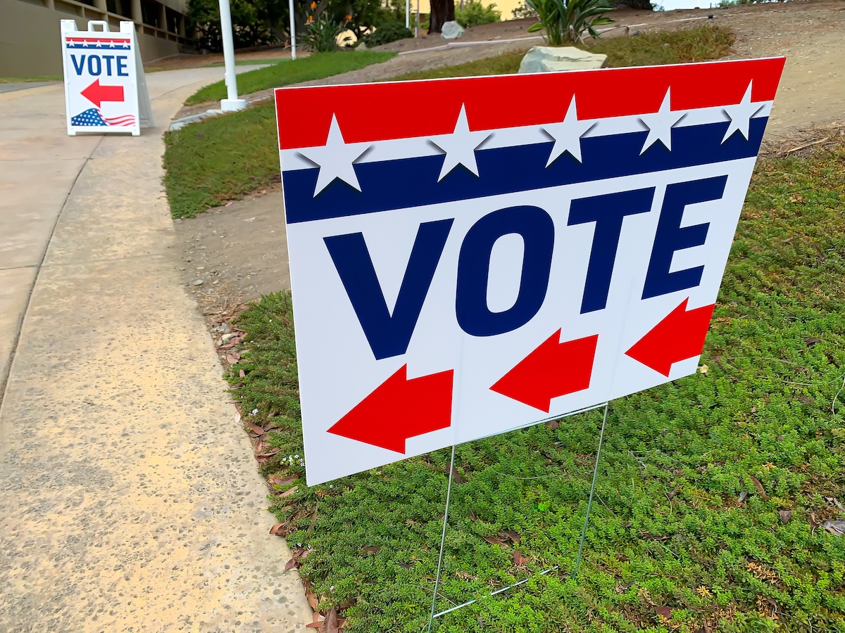 Red, white and blue sign with an arrow indicating where to go to vote.