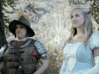 A woman dressed as a princess and a man dressed as a medieval soldier in a forested area