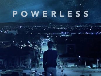 A man standing on a rooftop overlooking a large city at night with the word Powerless above him