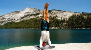 Andre Haralyi doing a headstand near a lake with mountains in the distance