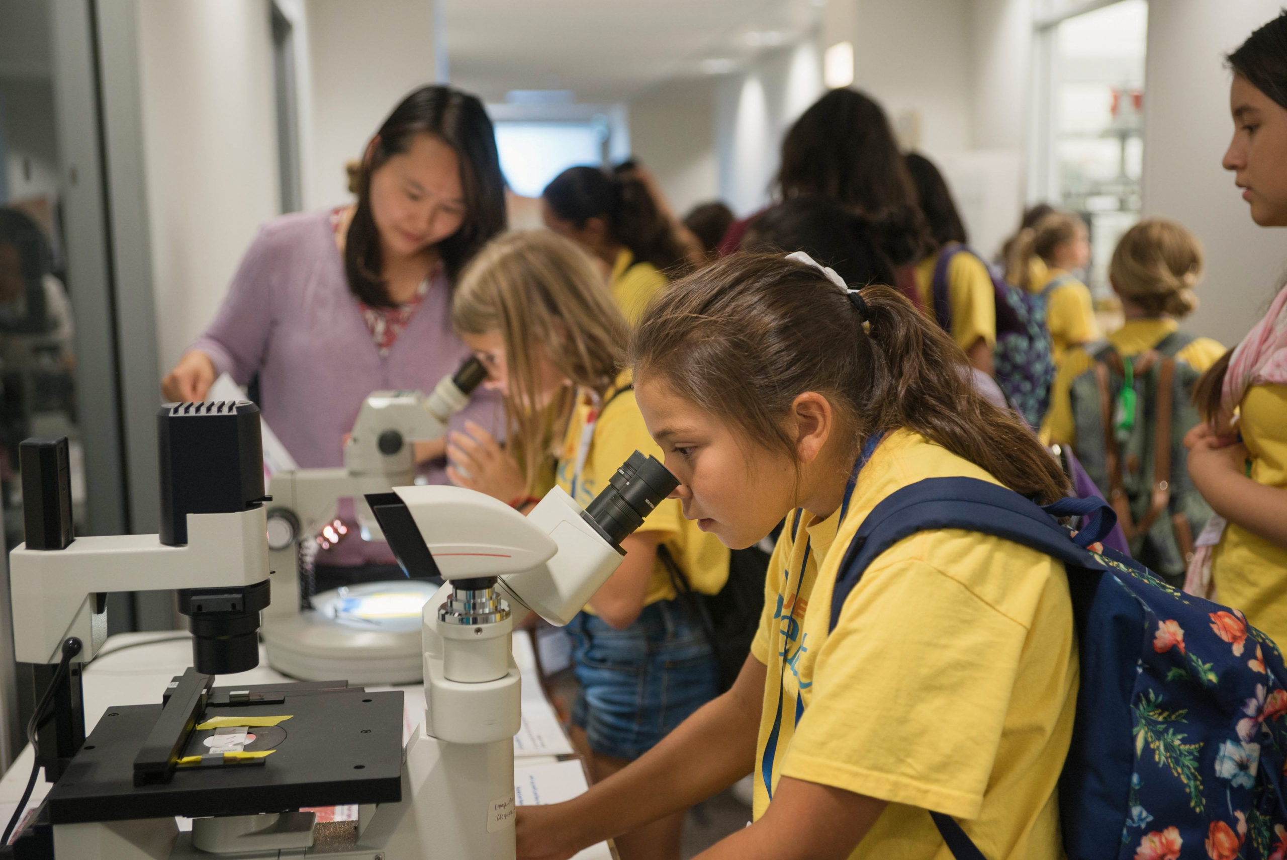 Young girl looking into microscope at a STEM Summer session