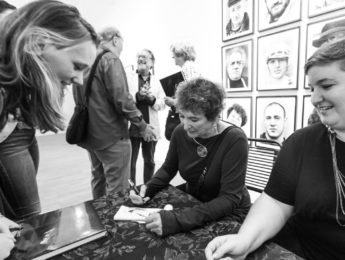 Black and white shot of Judy Dater signing autographs at "Only Human" exhibit