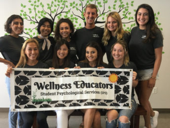 Students standing with Wellness Educators Banner