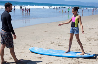 LMU MBA alumnus Ben Perreira '12 gives surf lessons to a child from Big Brothers Big Sisters
