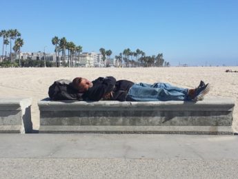 Homeless man napping at the beach