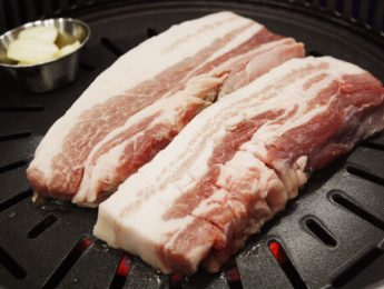 A colorful closeup of pork belly at a Korean BBQ restaurant.