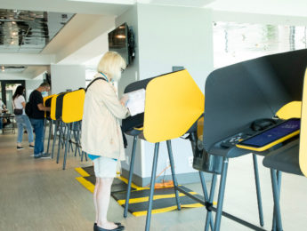 Woman voting at yellow booth.