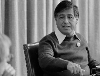 A black and white photo of Cesar Chavez meeting with others at a table seated.