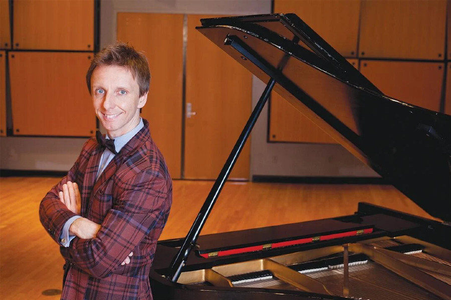 Wojciech Kocyan leaning against a piano
