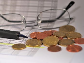 glasses, coin and pen sitting on spreadsheet