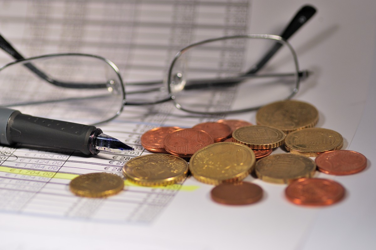 glasses, coin and pen sitting on spreadsheet