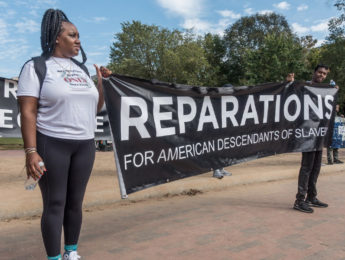 Activists hold a sign pushing for reparations for American descendants of enslaved people.