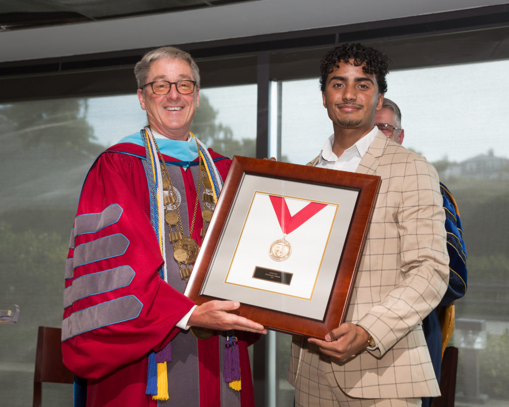 Image of President Snyder presenting the Valedictorian Award to Christian H. Jackson
