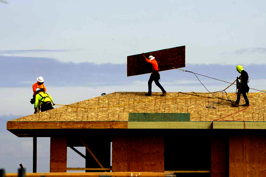 workers on roof of house under construction