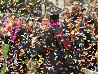 Graduates celebrate at commencement with confetti flying through the air.