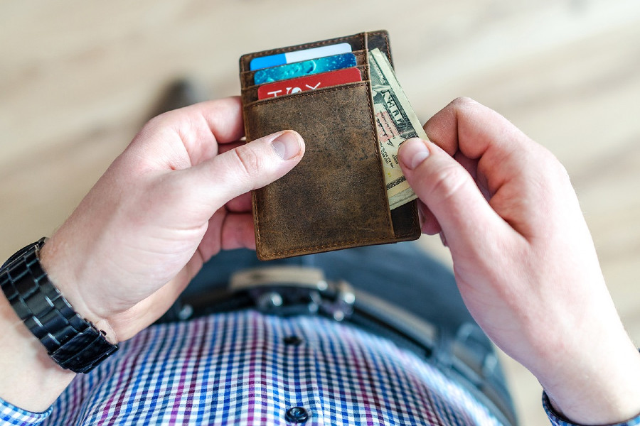 Man looking at credit cards and cash in wallet
