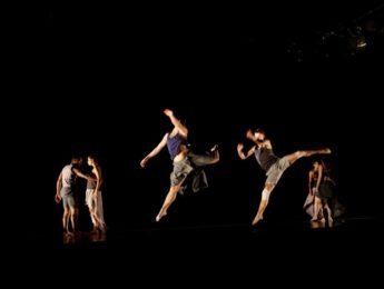 dancers leaping on stage against black backdrop