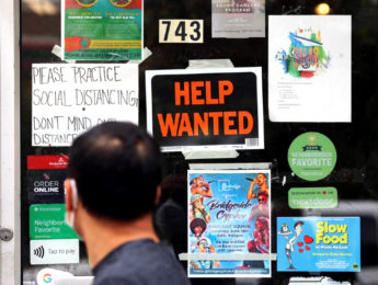man standing in front of help wanted sign