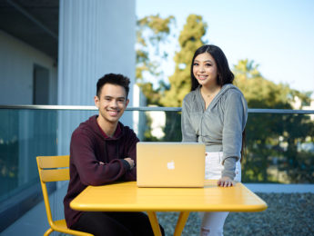 Male student Michael Elias and female student Megan Reyes in front of a laptop at a table