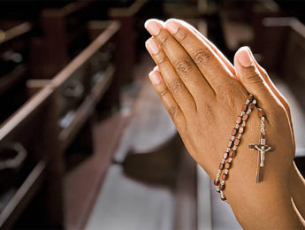 Image of Hands Praying in Church With Rosary