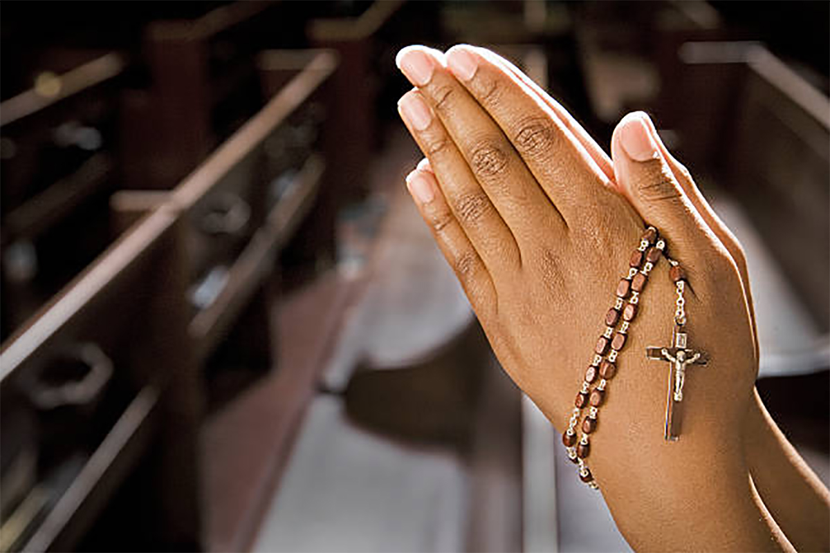 Image of Hands Praying in Church With Rosary