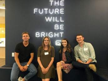 Students and alumni sitting in front of a sign saying The Future Will Be Bright