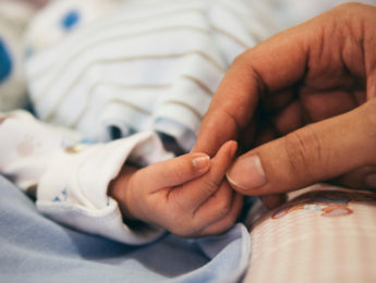 adult hand holding child's in hospital