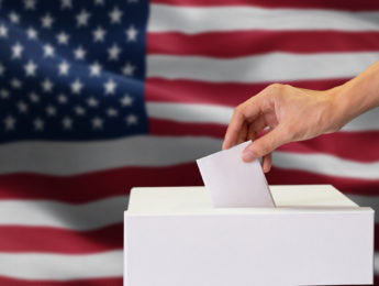 Close-up of man casting and inserting a vote and choosing and making a decision what he wants in polling box with United States flag blended in background