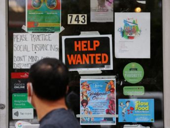man looks at help wanted sign