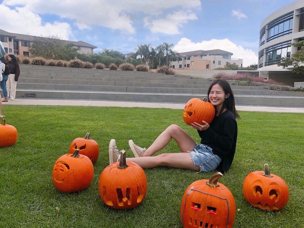 A student carves pumpkins on Lawton Plaza outside.
