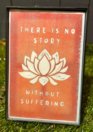 An orange sign displays the quote "There is no story without suffering."