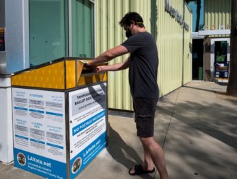 voters placing ballot into box