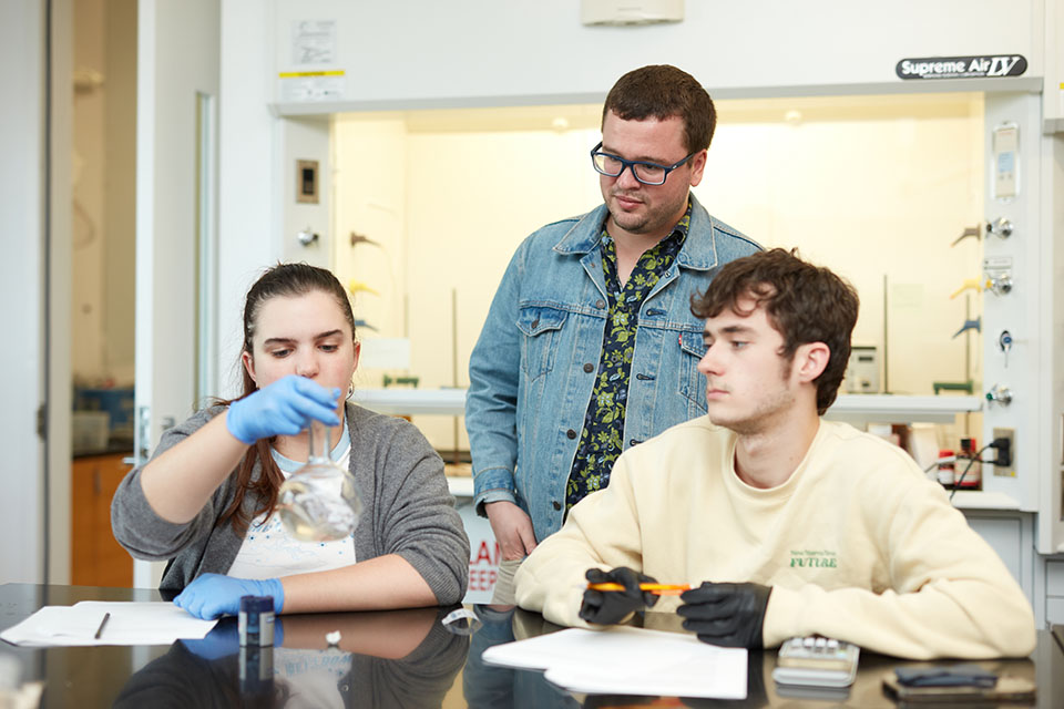 Professor Hunt working with two students at lab table